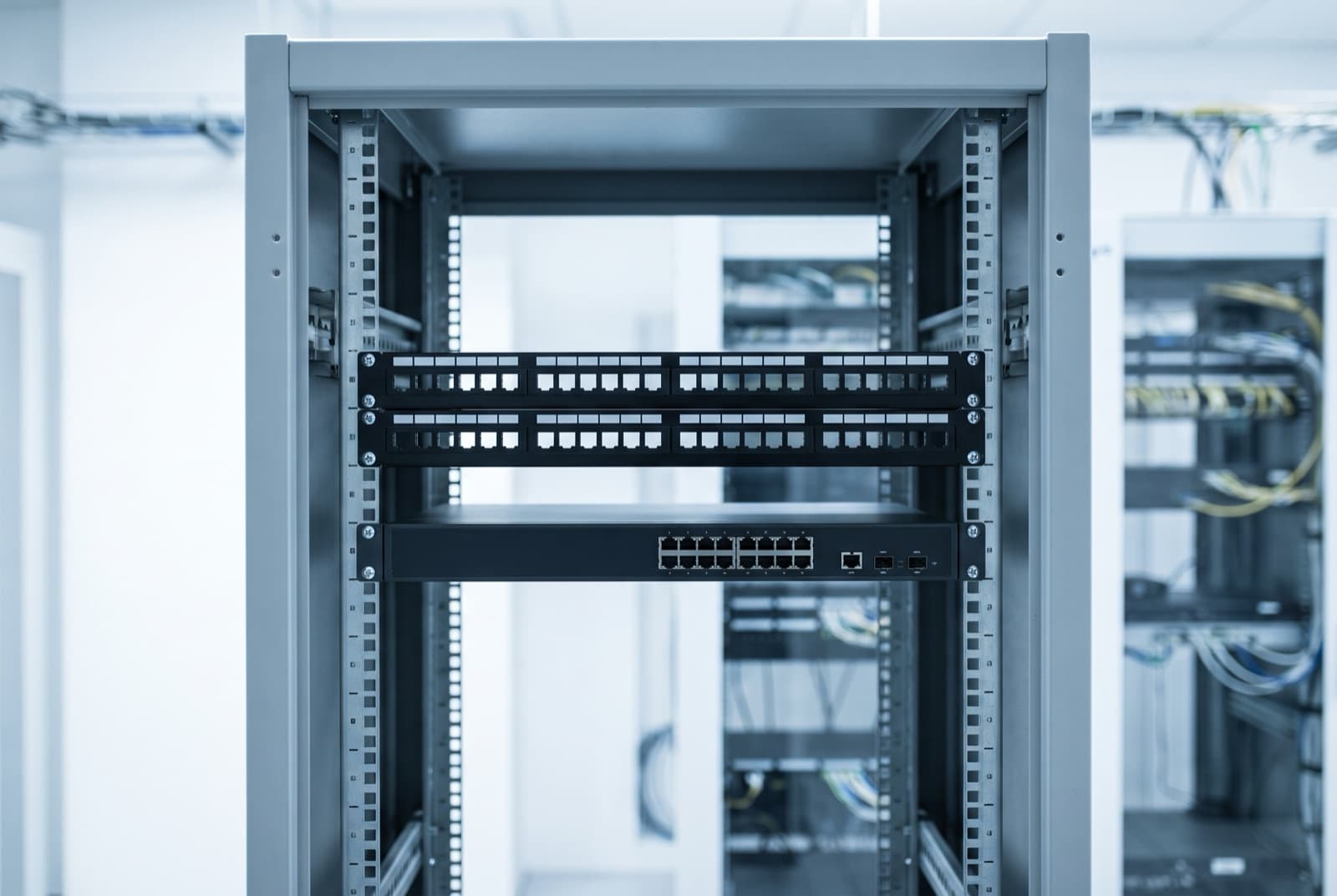 Open 19 inch server rack cabinet showing mounting rails, patch panels and rack unit spacing