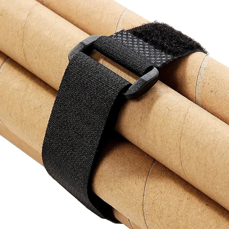Wall Ties: Black velcro strap securing cardboard tubes on a light background.