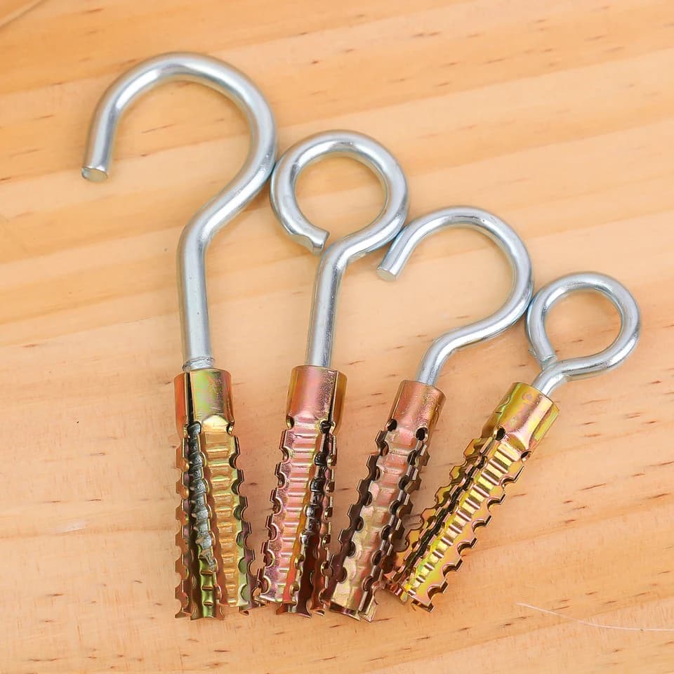 Concrete screws: four metal hooks with anchors on a light wooden background.