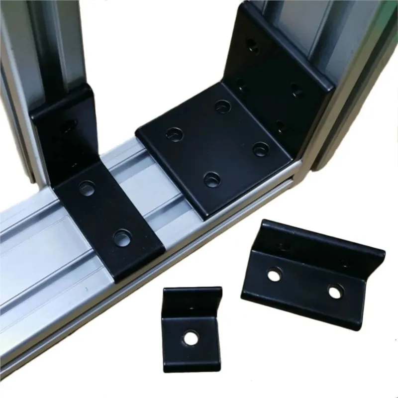 L brackets, black, some attached to aluminium extrusions, some loose on white.