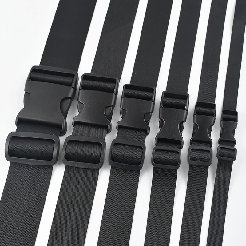 Side release buckles in various sizes, black plastic with webbing straps on white.
