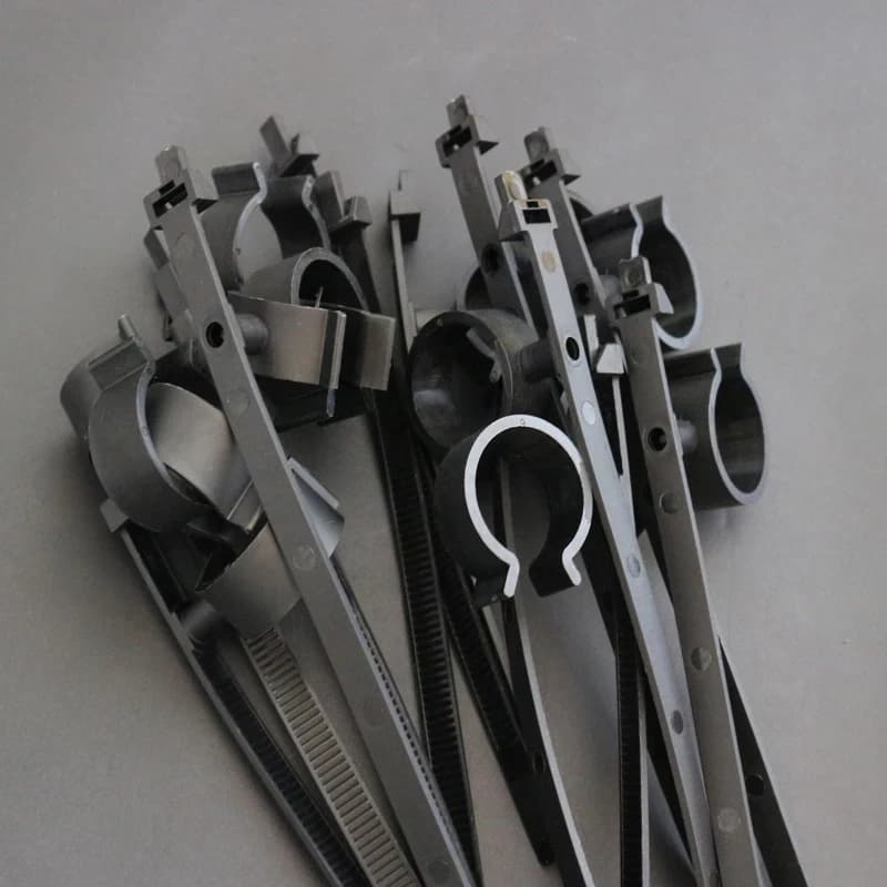 Cavity wall ties: black plastic cable ties with integrated clips, piled on a light grey background.