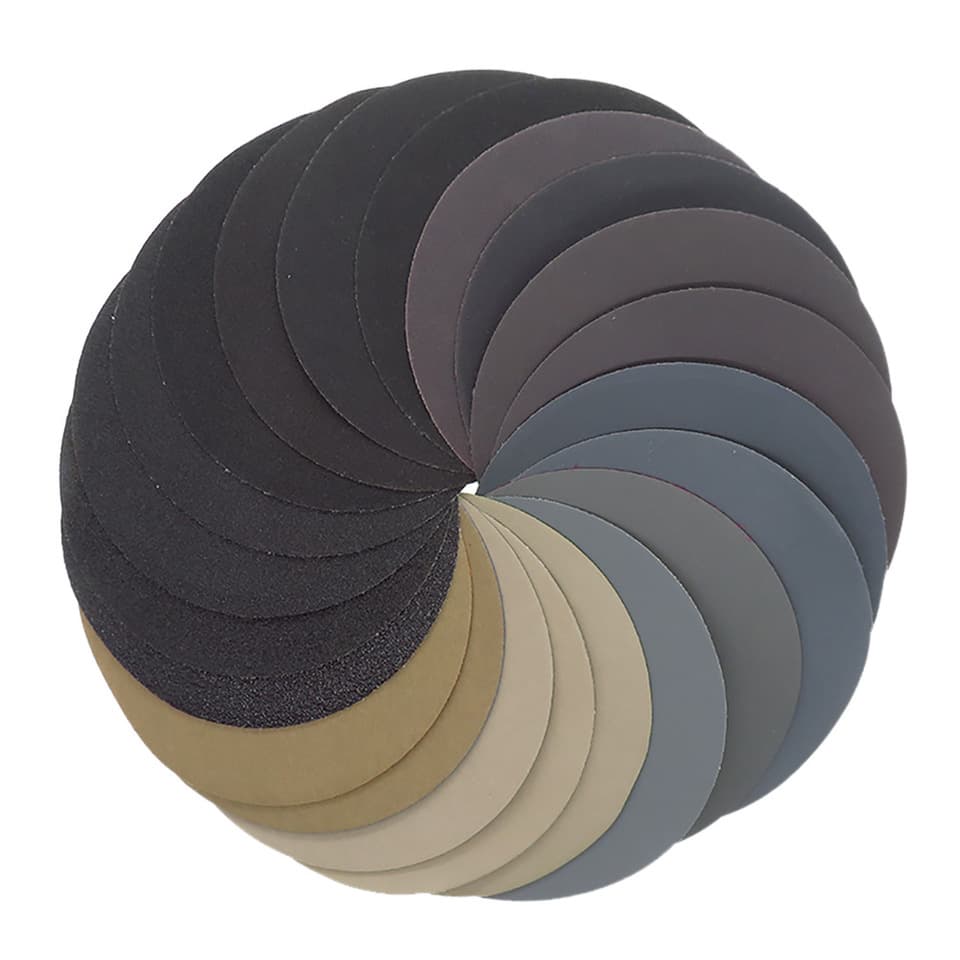 A stack of 5-inch round sandpaper discs with 8 holes, ranging from 60 to 10000 grit, for a bench sander.