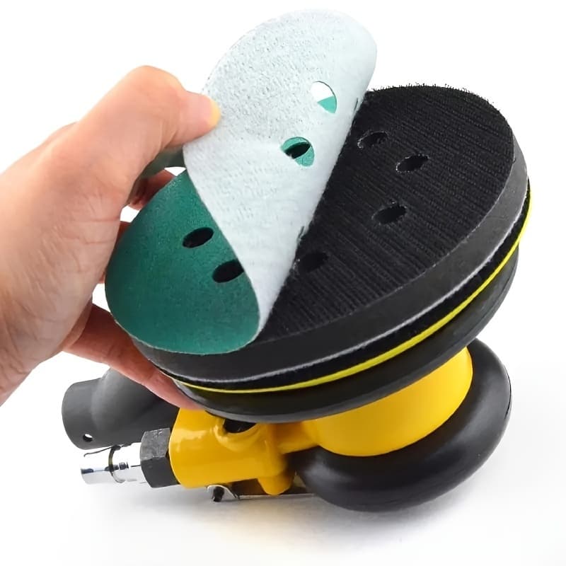 A black 125mm soft sponge interface pad with 8 holes, designed for an orbital sander pad to reduce impact noise.
